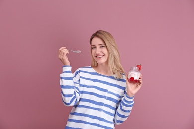 Photo of Young attractive woman eating tasty yogurt on color background