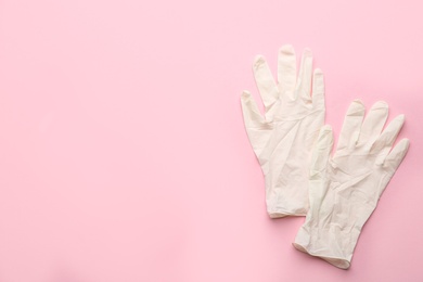 Photo of Pair of medical gloves on pink background, flat lay. Space for text