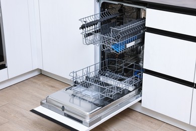 Photo of Open clean empty dishwasher in kitchen. Home appliance