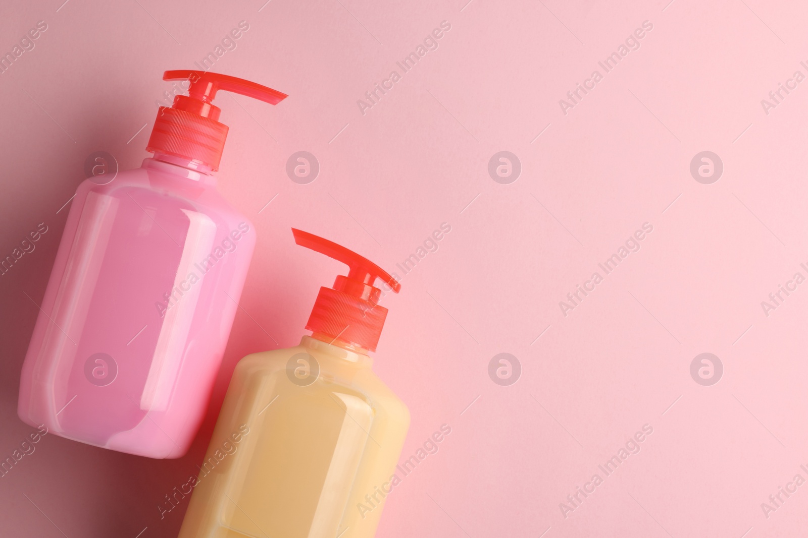 Photo of Bottles of liquid soap on pink background, flat lay. Space for text