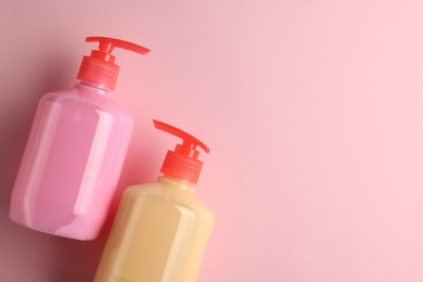 Bottles of liquid soap on pink background, flat lay. Space for text