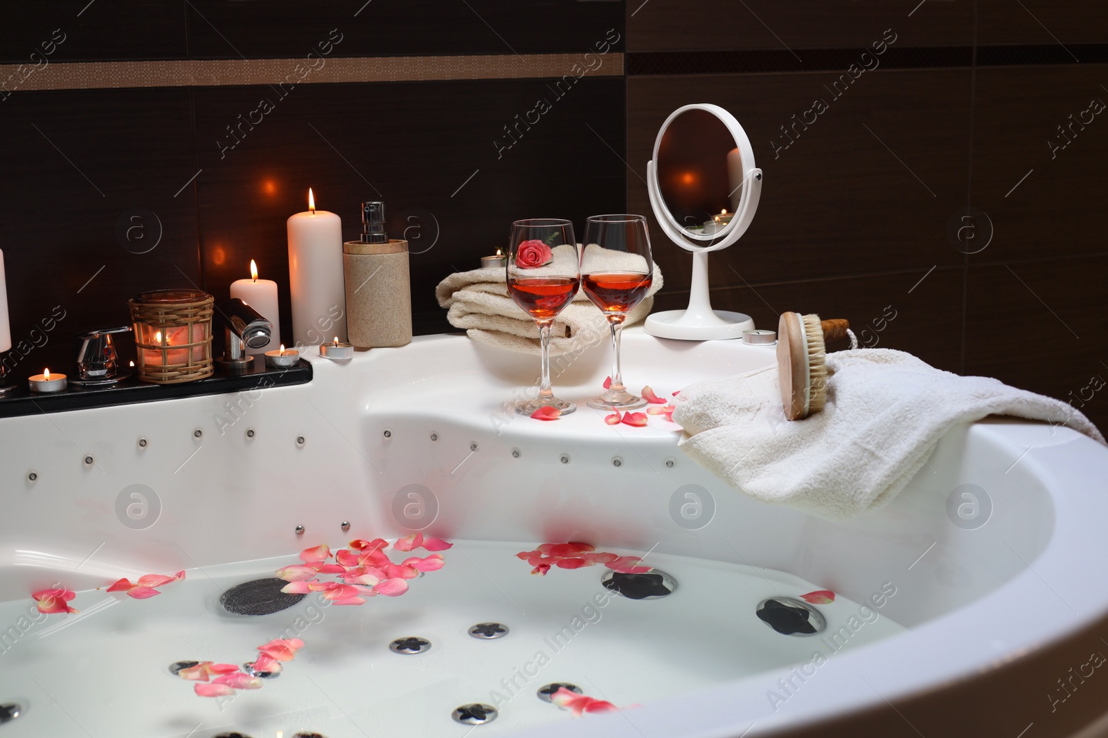 Photo of Bathtub with glasses of wine and candles indoors. Romantic atmosphere