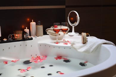 Photo of Bathtub with glasses of wine and candles indoors. Romantic atmosphere