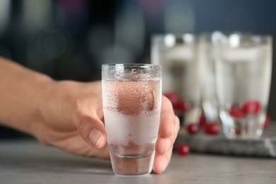 Woman with shot of vodka at table in bar, closeup