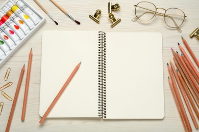 Flat lay composition with blank sketchbook on white wooden table. Space for text