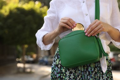 Photo of Woman taking cosmetic pocket mirror from bag outdoors, closeup