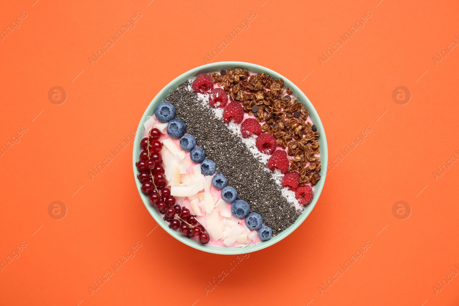 Photo of Tasty smoothie bowl with fresh berries and granola on orange background, top view