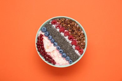 Photo of Tasty smoothie bowl with fresh berries and granola on orange background, top view