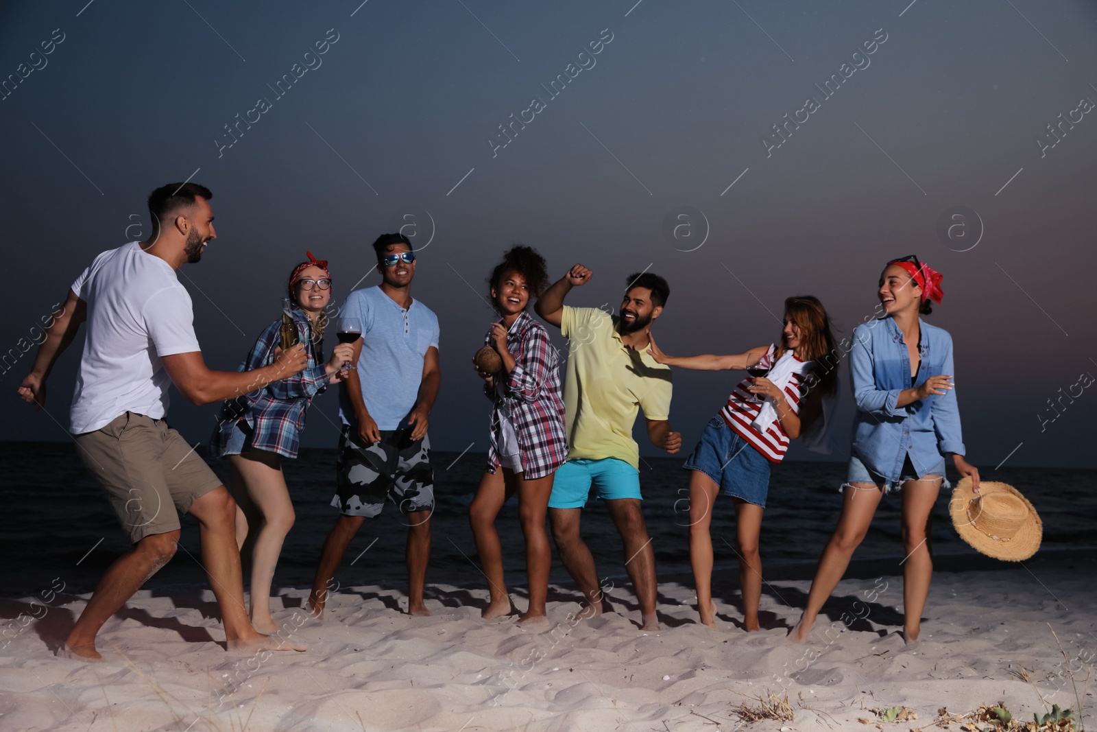 Photo of Happy friends enjoying summer beach party in evening