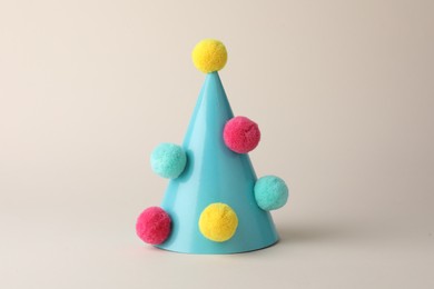One light blue party hat with pompoms on beige background