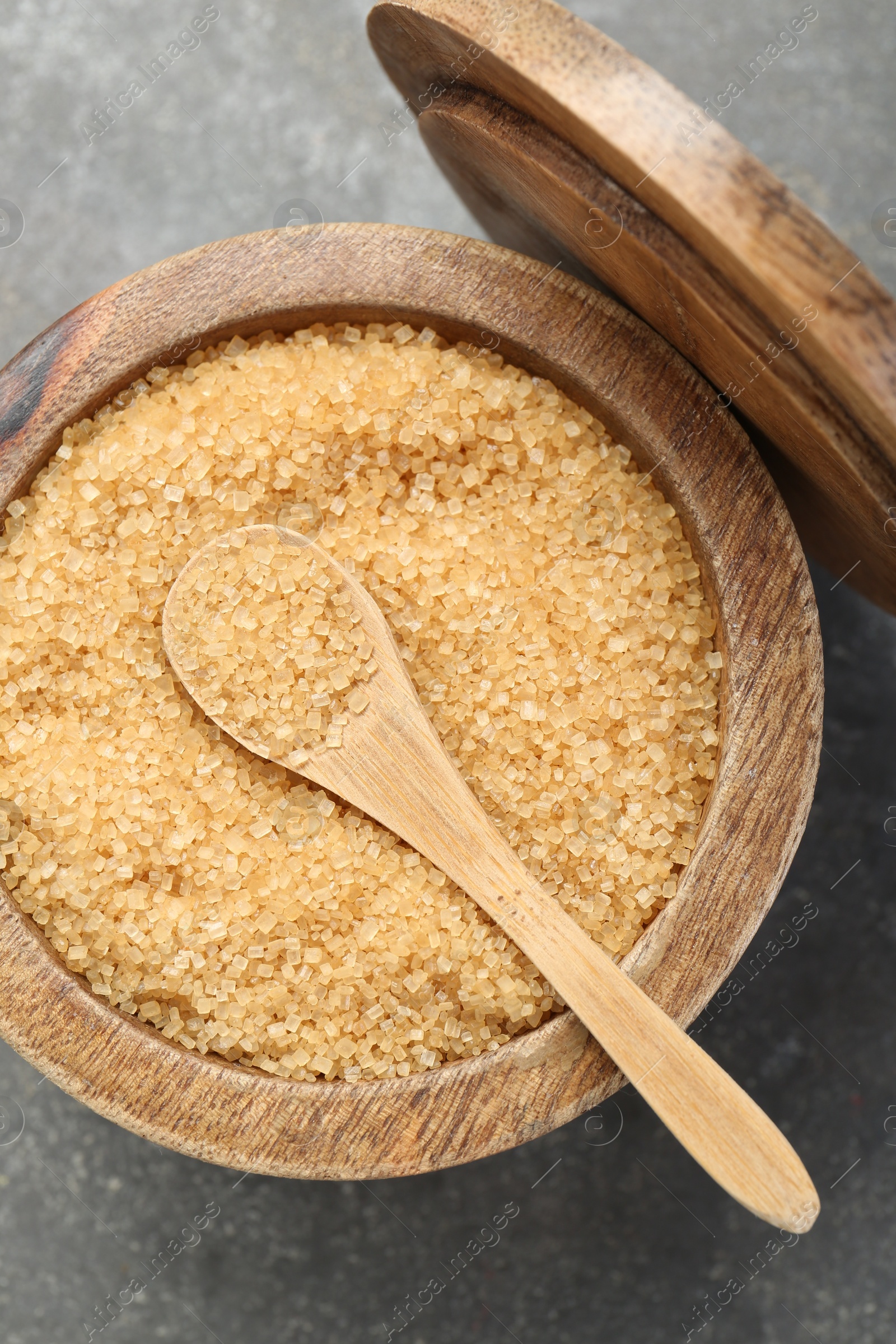 Photo of Brown sugar in bowl and spoon on grey textured table, top view