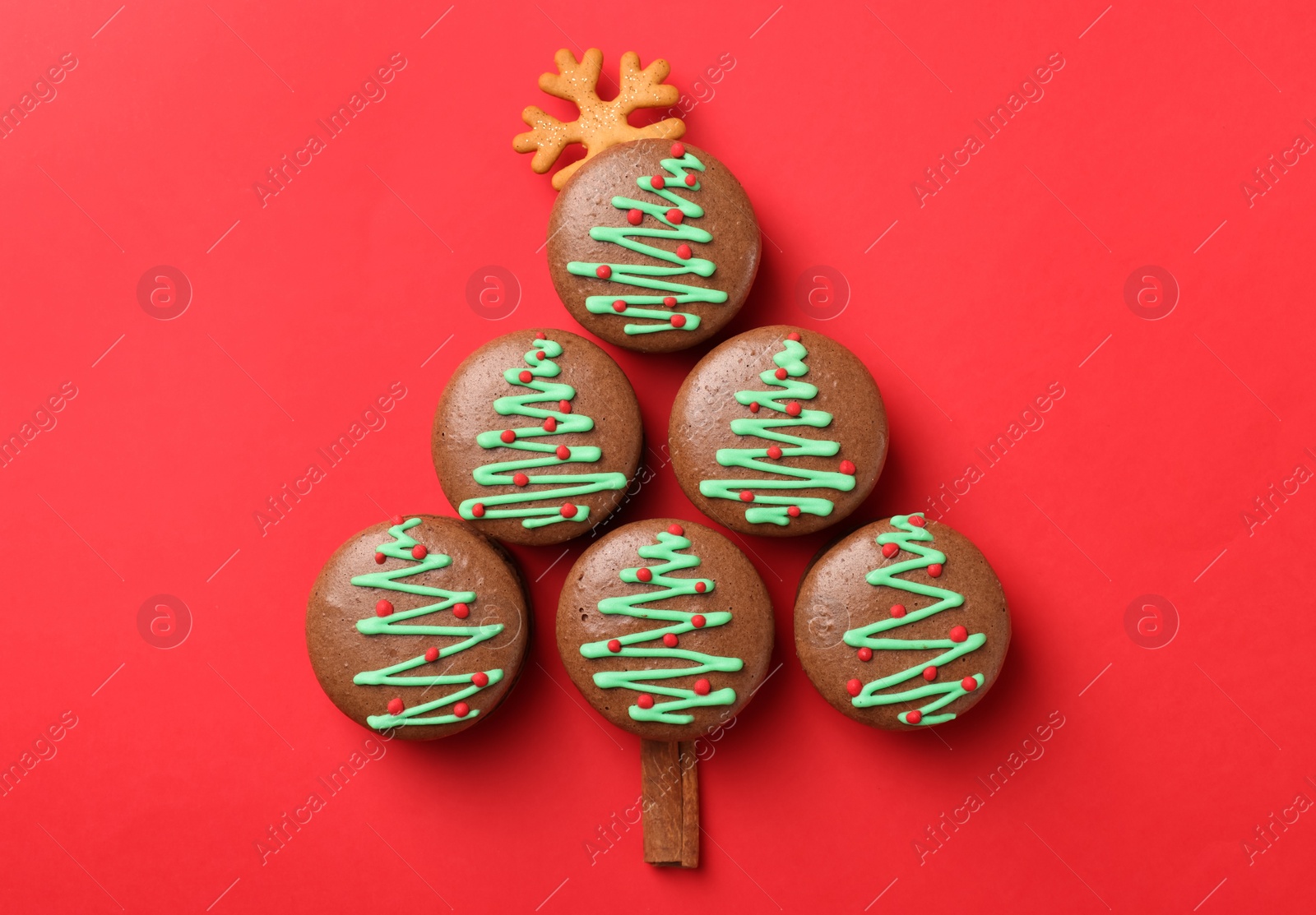 Photo of Beautifully decorated Christmas macarons on red background, flat lay