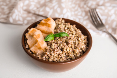 Photo of Tasty buckwheat porridge with meat on white table