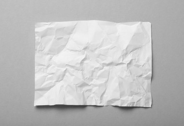 Photo of Sheet of white crumpled paper on grey background, top view