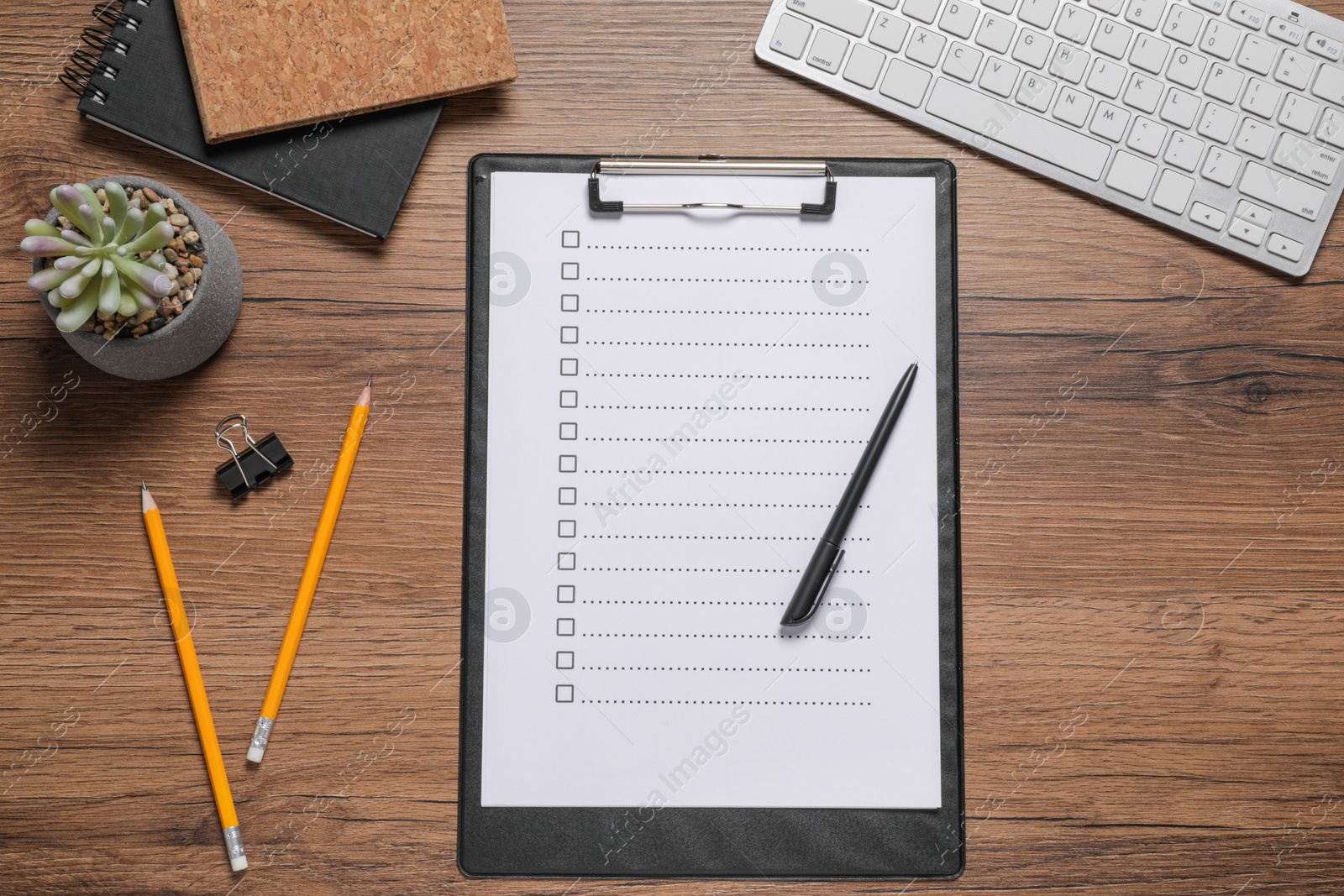 Photo of Clipboard with checkboxes, computer keyboard and plant on wooden table, flat lay. Checklist