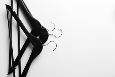 Black hangers on white background, top view. Space for text