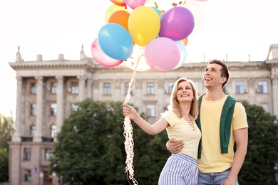 Photo of Young couple with colorful balloons outdoors on sunny day