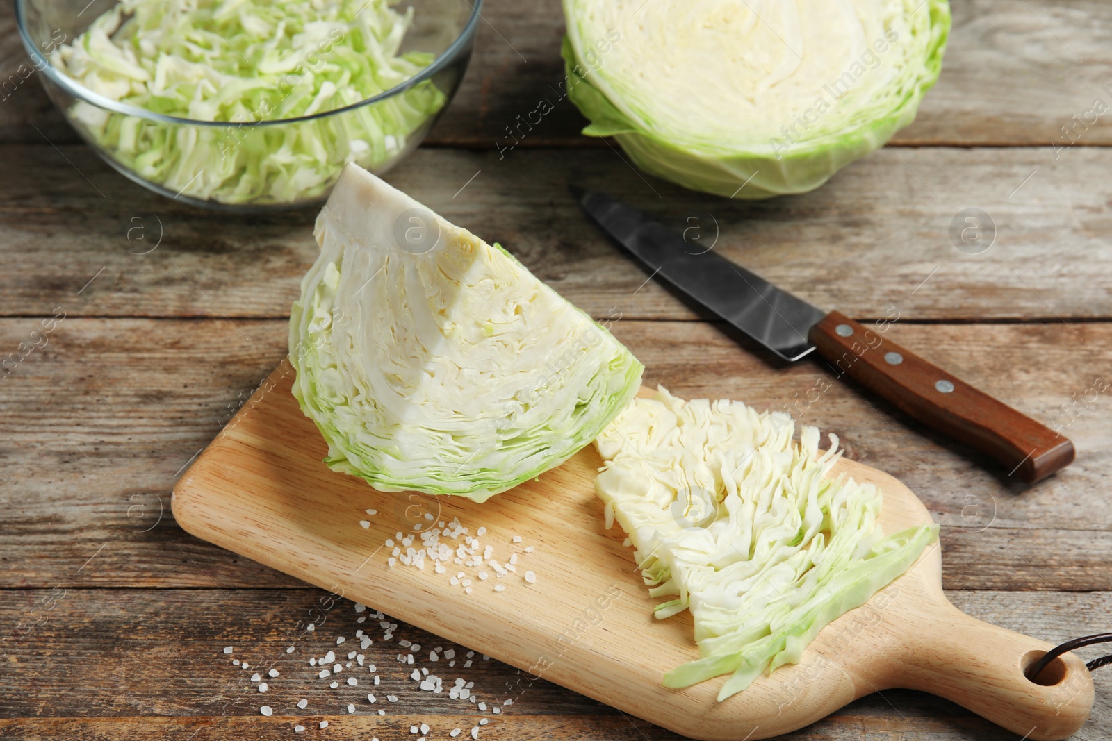 Photo of Cutting board with chopped and sliced cabbage on table