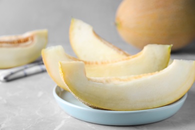 Pieces of delicious honeydew melon on light grey marble table