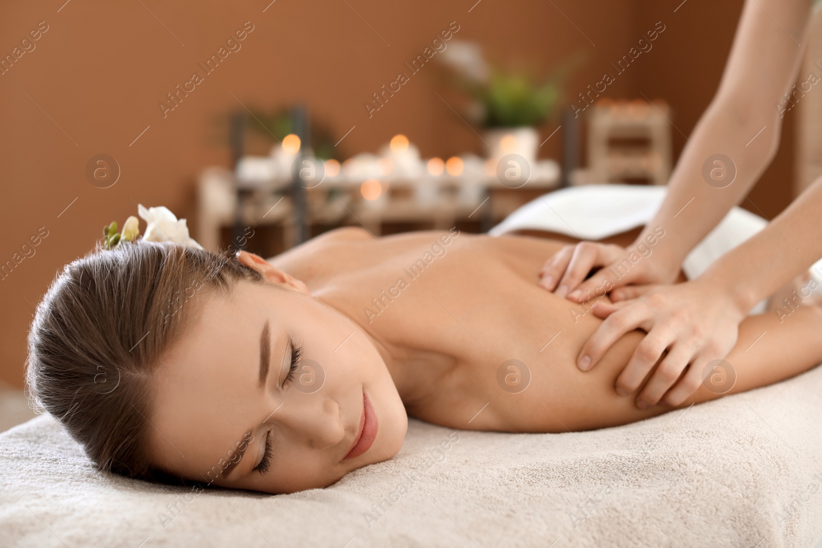 Photo of Young woman enjoying massage in spa salon