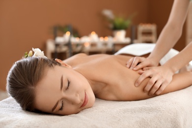 Photo of Young woman enjoying massage in spa salon