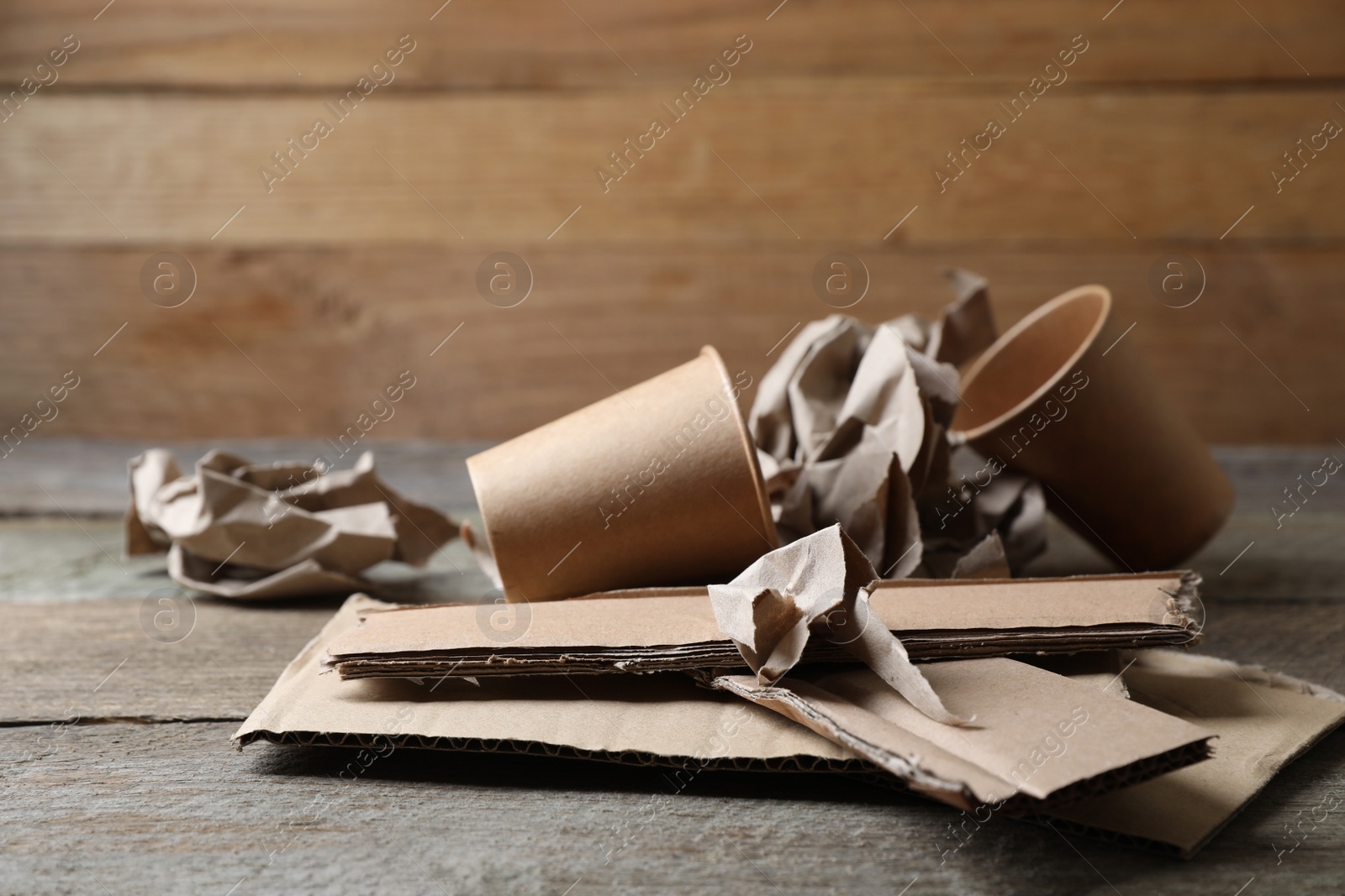 Photo of Different waste paper on wooden table near wall