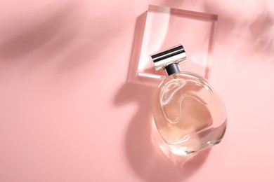 Photo of Bottle of luxury women's perfume in sunlight on pink background, top view. Space for text