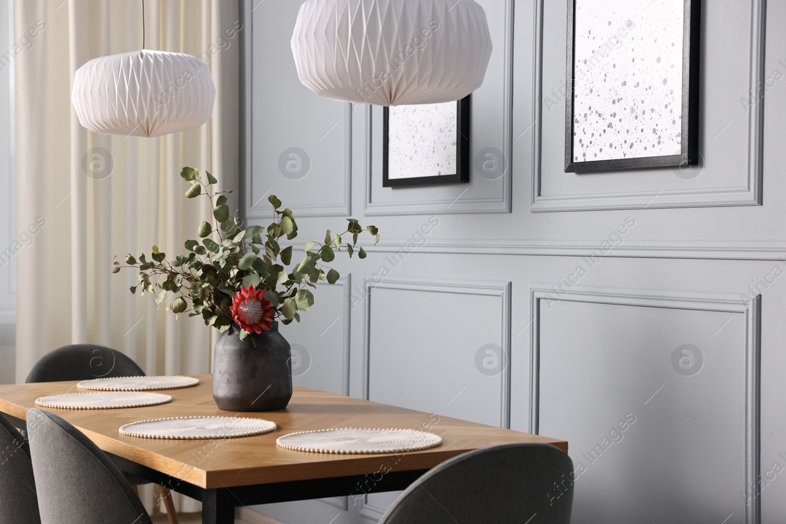 Photo of Soft chairs, table and vase with plants in stylish dining room