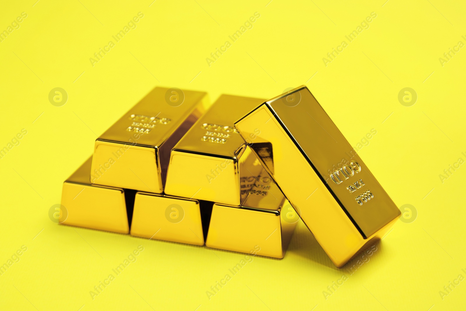 Photo of Many shiny gold bars on yellow background