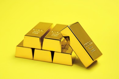Photo of Many shiny gold bars on yellow background