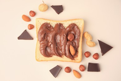 Photo of Tasty toast with chocolate paste and nuts on beige background, flat lay