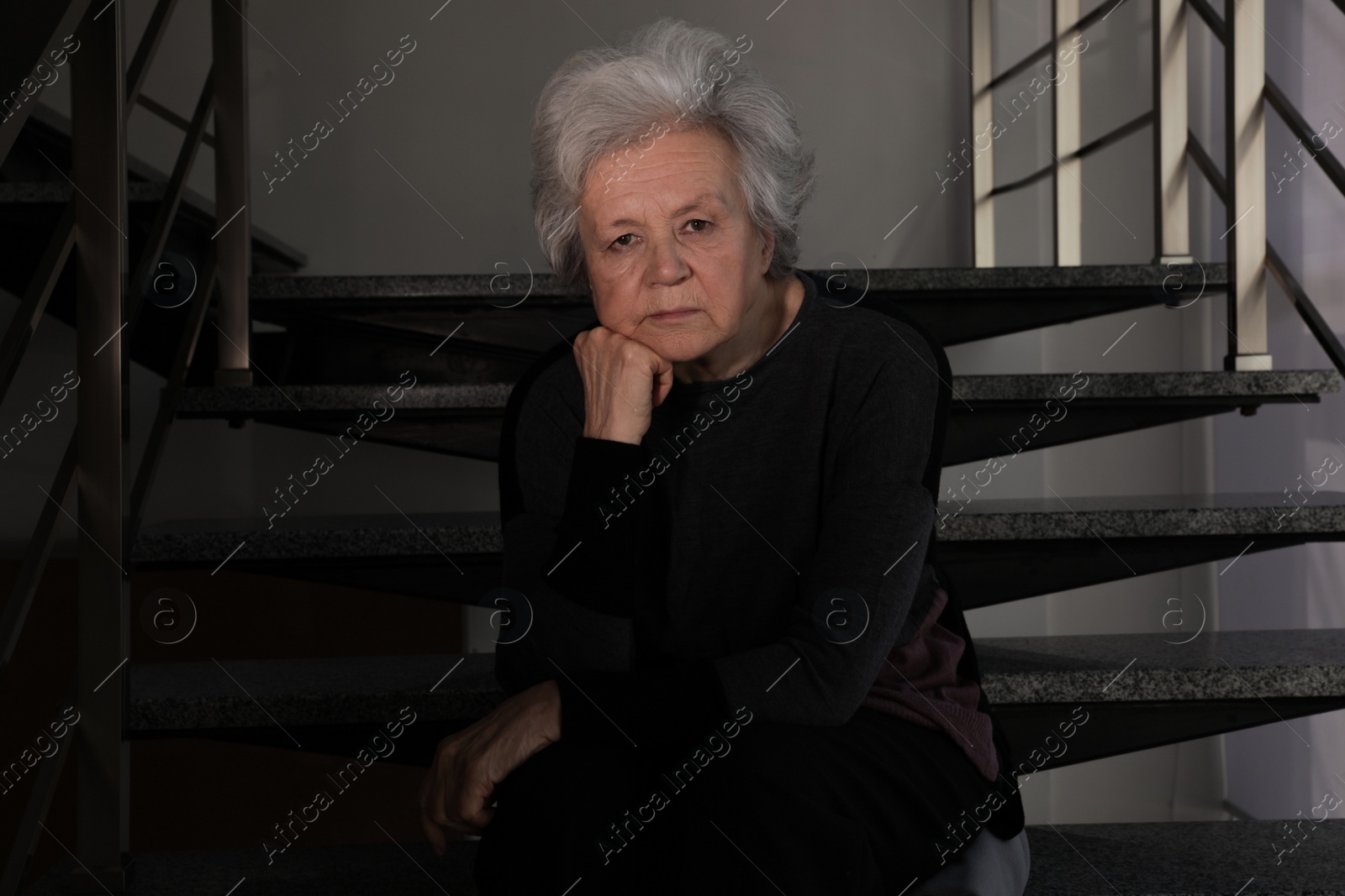 Photo of Portrait of poor mature woman sitting on stairs