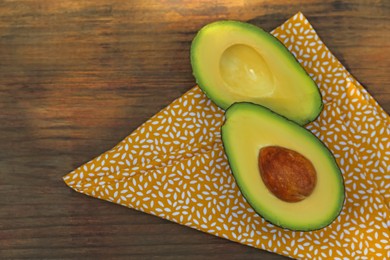 Photo of Halves of fresh avocado on wooden table, flat lay