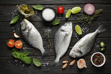 Flat lay composition with raw dorada fish on black wooden table