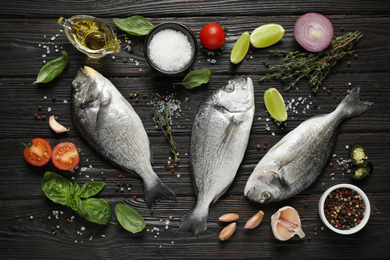 Photo of Flat lay composition with raw dorada fish on black wooden table