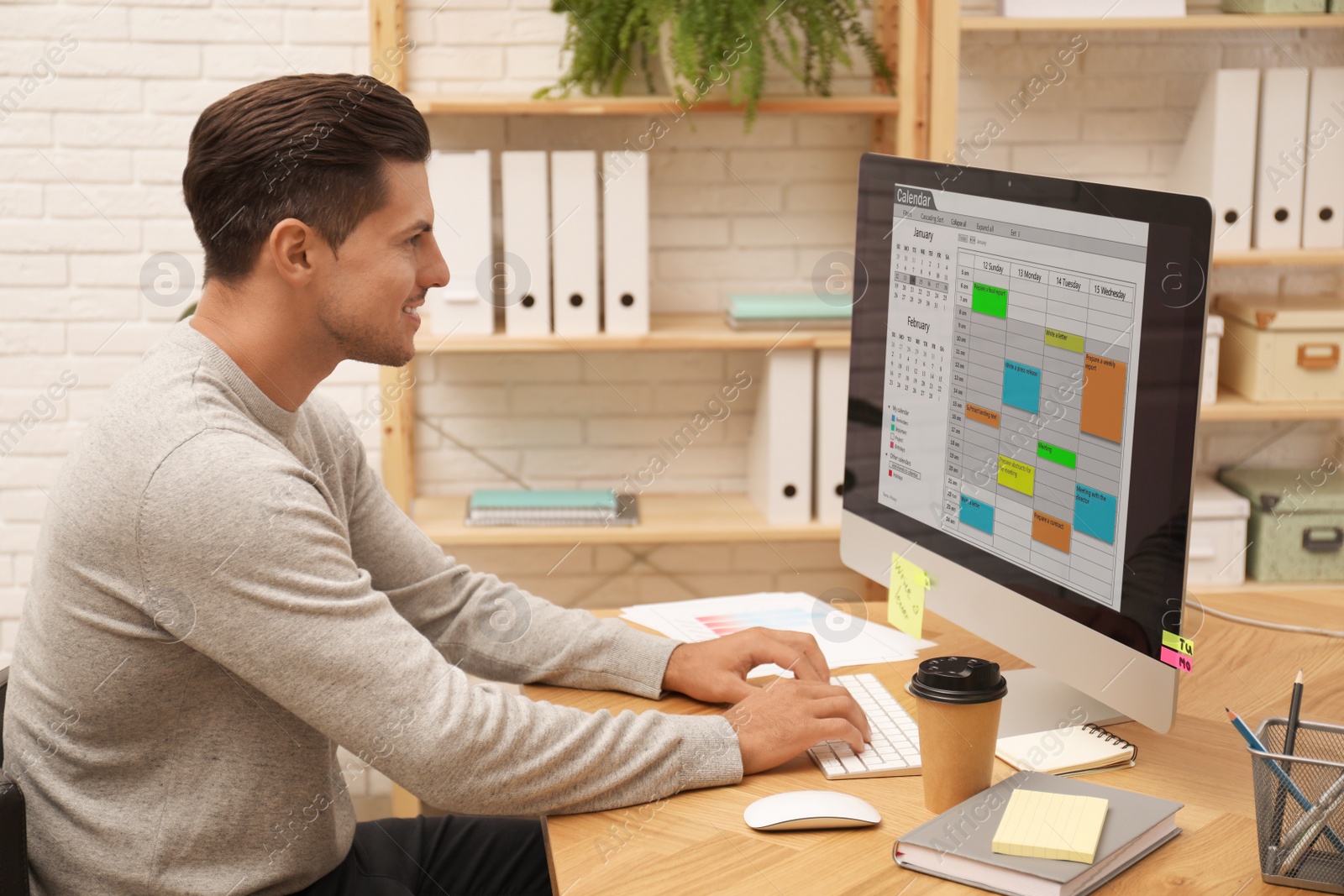 Photo of Handsome man using calendar app on computer in office