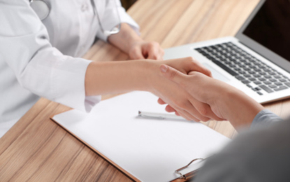 Doctor and patient shaking hands in office, closeup. Medical service