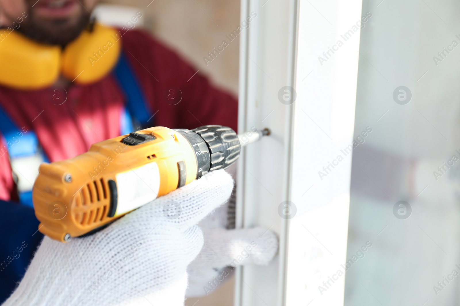 Photo of Workers using electric screwdriver for window installation indoors, closeup
