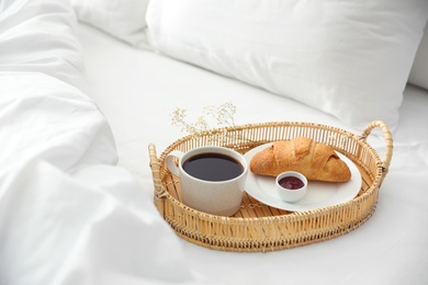 Tray with tasty breakfast on white bed