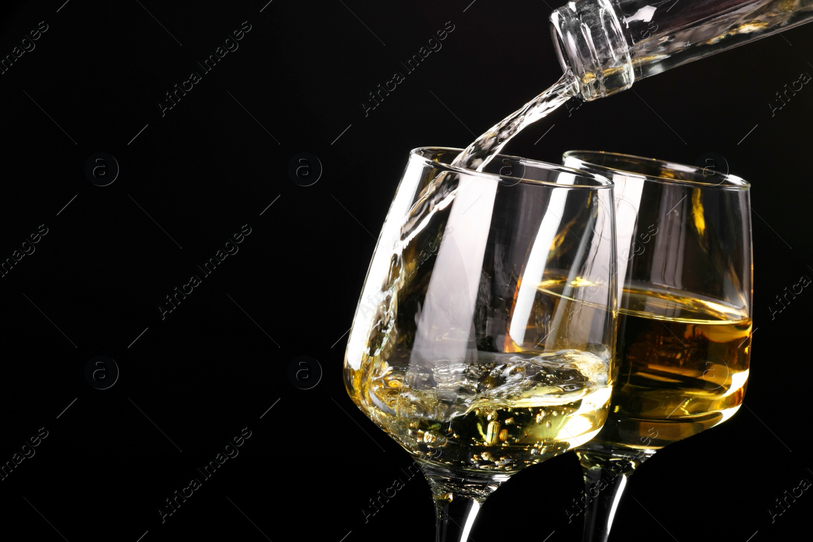 Photo of Pouring tasty aromatic wine in glass on black background, closeup. Space for text