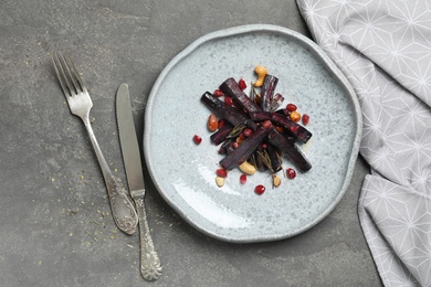Photo of Tasty baked black carrot served on grey table, flat lay