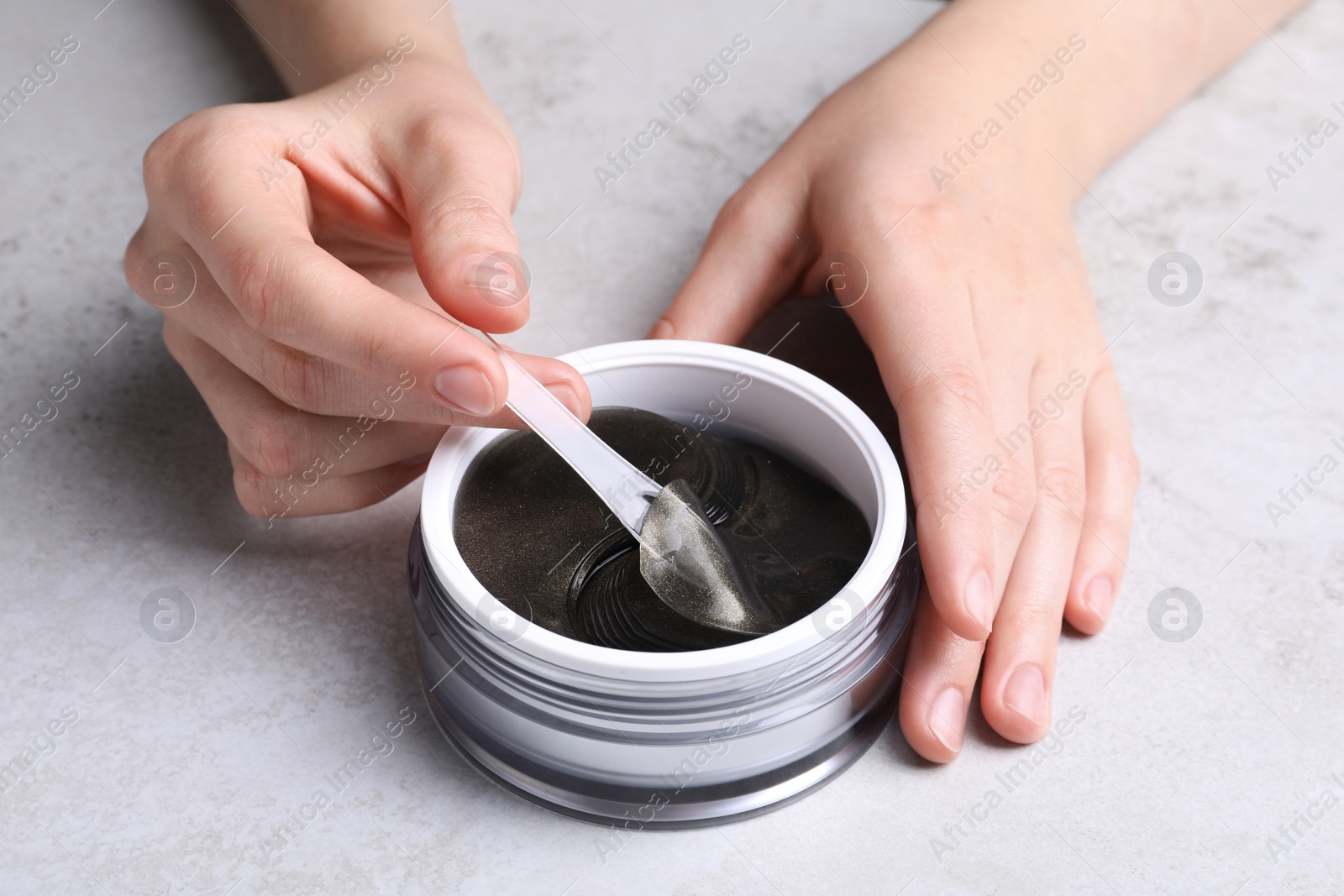 Photo of Woman using under eye patches at light table, closeup. Cosmetic product