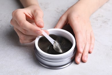 Photo of Woman using under eye patches at light table, closeup. Cosmetic product