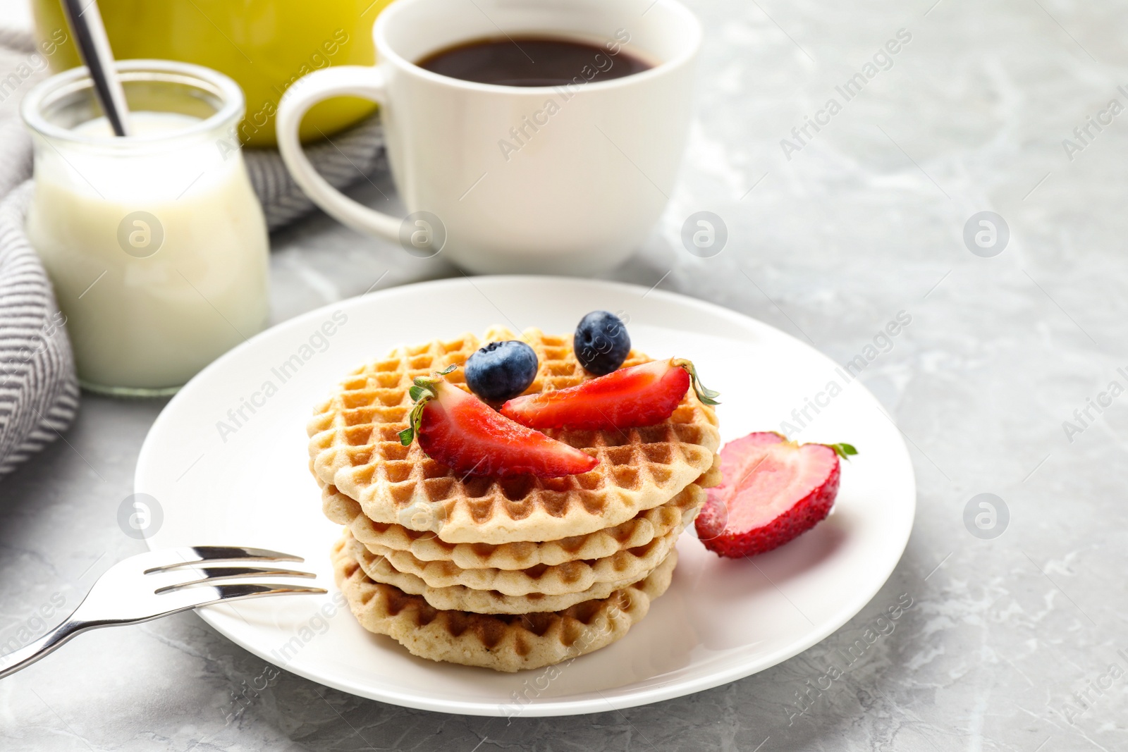 Photo of Tasty breakfast with wafers served on light grey marble table