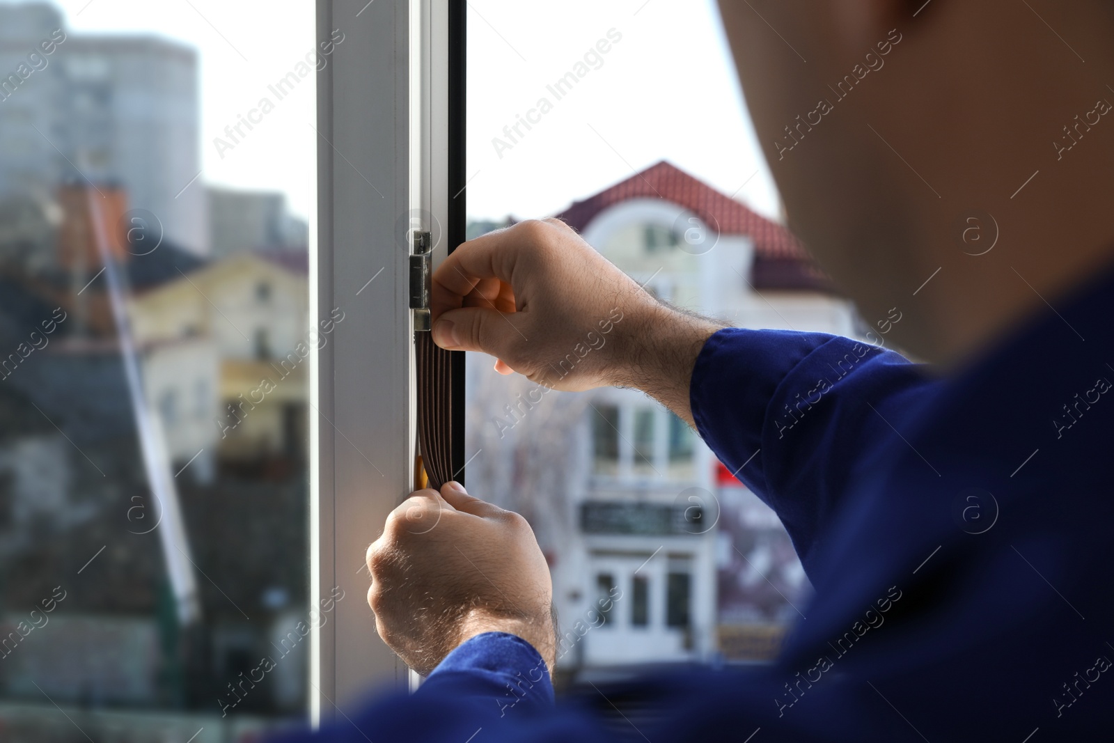 Photo of Construction worker putting sealing foam tape on window indoors, closeup