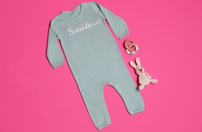 Baby clothes and toys on pink background, flat lay