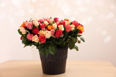 Bouquet of beautiful roses on wooden table against beige background