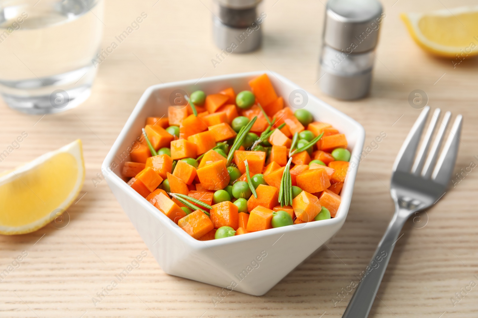 Photo of Tasty salad with fresh carrot in bowl on wooden table