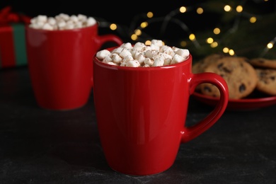 Photo of Cup of delicious hot cocoa with marshmallows on black table