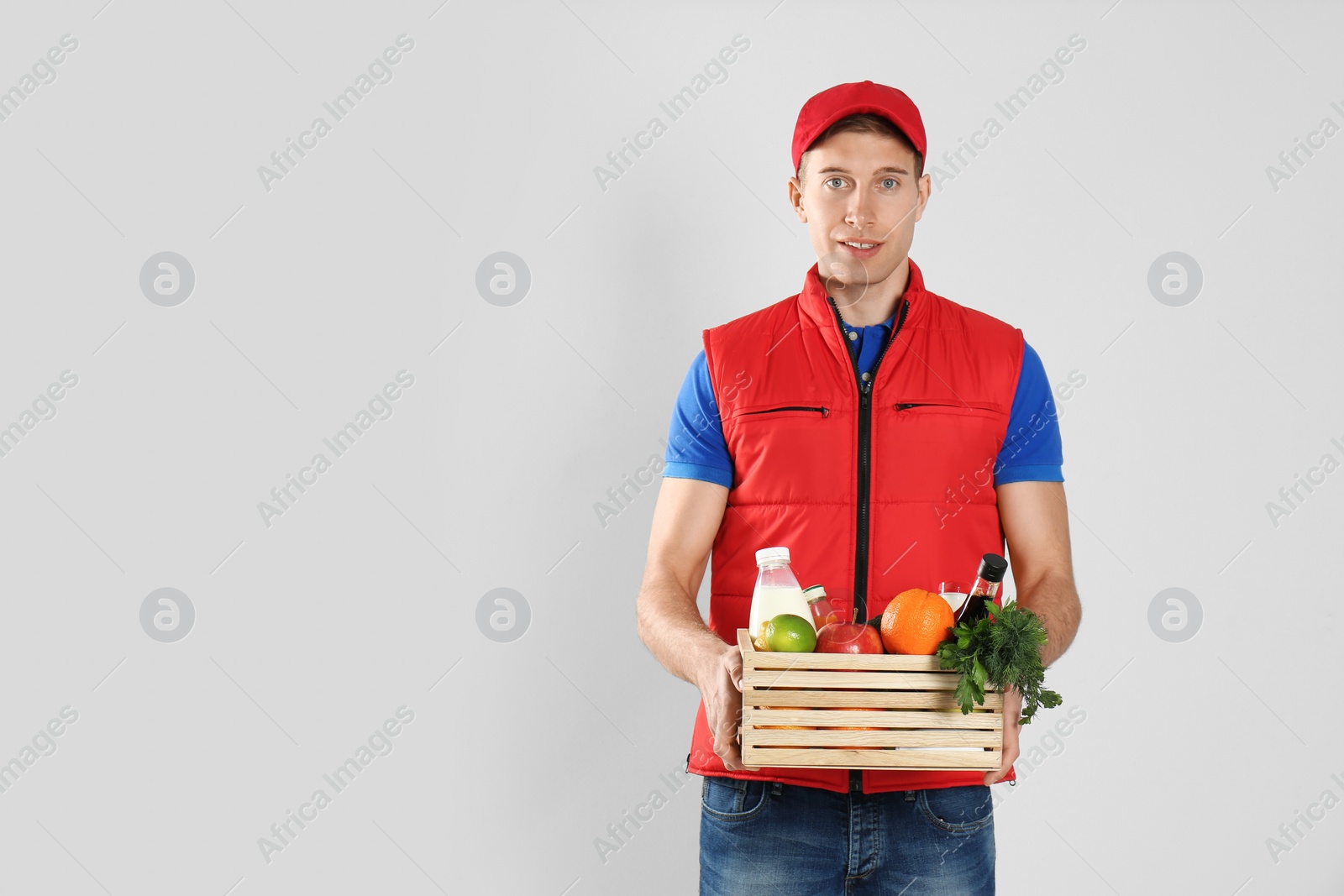 Photo of Courier with fresh products on light background, space for text. Food delivery service